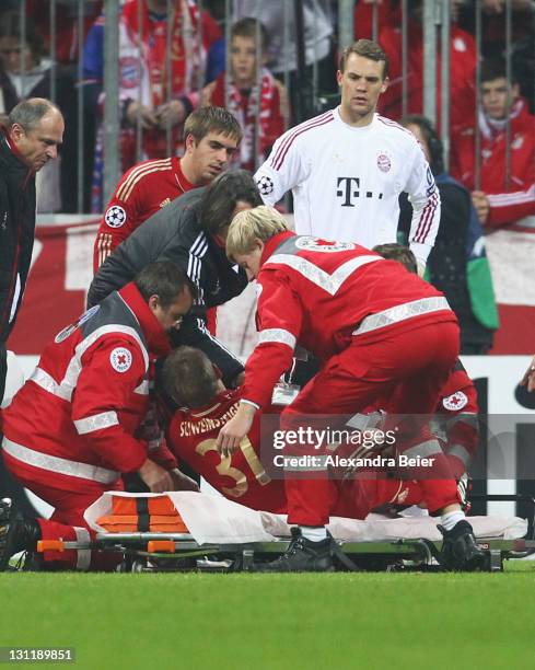 Bastian Schweinsteiger of Bayern Muenchen is laid down on a stretcher as teammates Philipp Lahm and goalkeeper Manuel Neuer watch him during the UEFA...