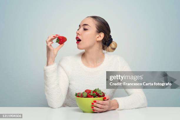 hispanic woman young woman eats fresh strawberries - woman eating fruit stock pictures, royalty-free photos & images