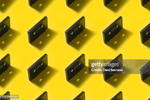 cassette tapes repetitive pattern on yellow background - audio cassettes photos et images de collection