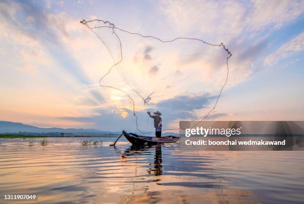 throwing fishing net during sunrise, thailand - fischnetz stock-fotos und bilder