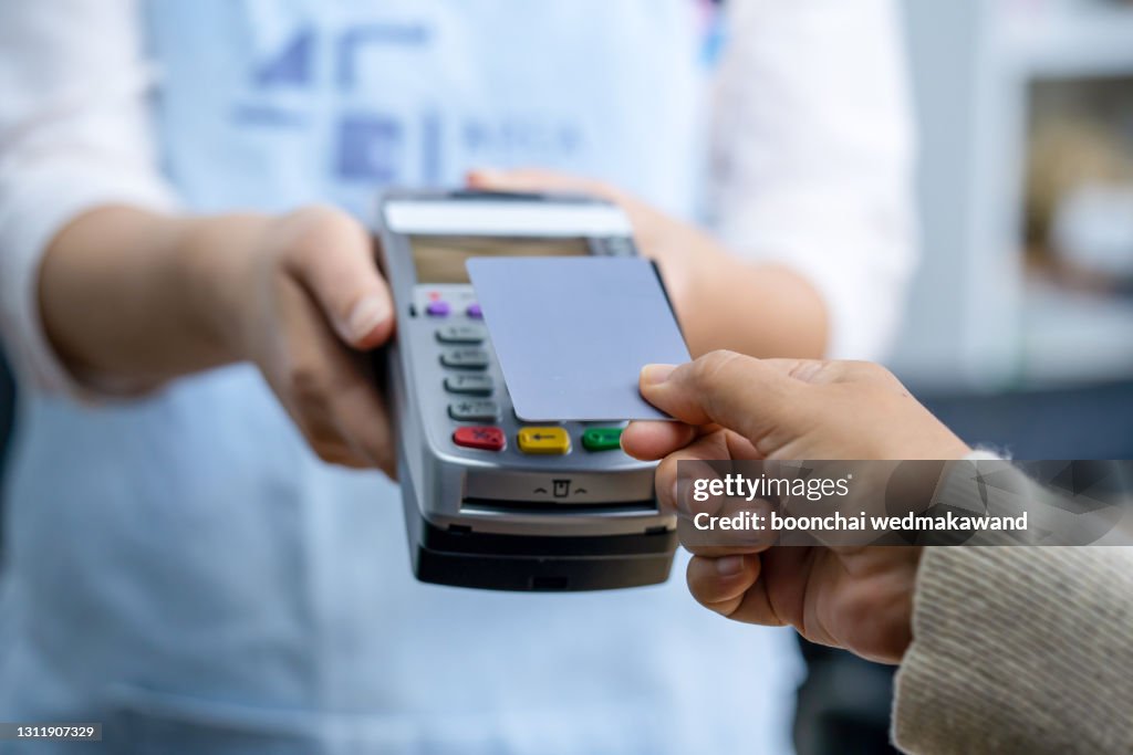 Customer using credit card for payment to owner at cafe restaurant, cashless technology and credit card payment concept