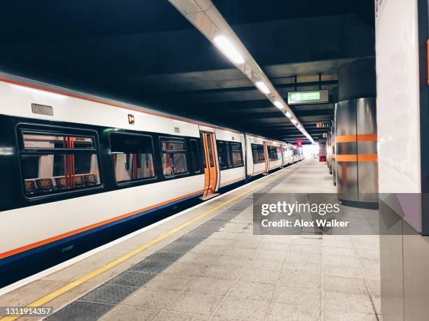 commuter train in covered station platform - train platform photos et images de collection