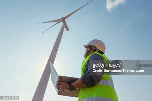middle aged engineer using digital laptop for inspect quality control efficiency wind turbine for generating electric power, renewable energy, clean energy or environment conservation concept. - people in air stock-fotos und bilder