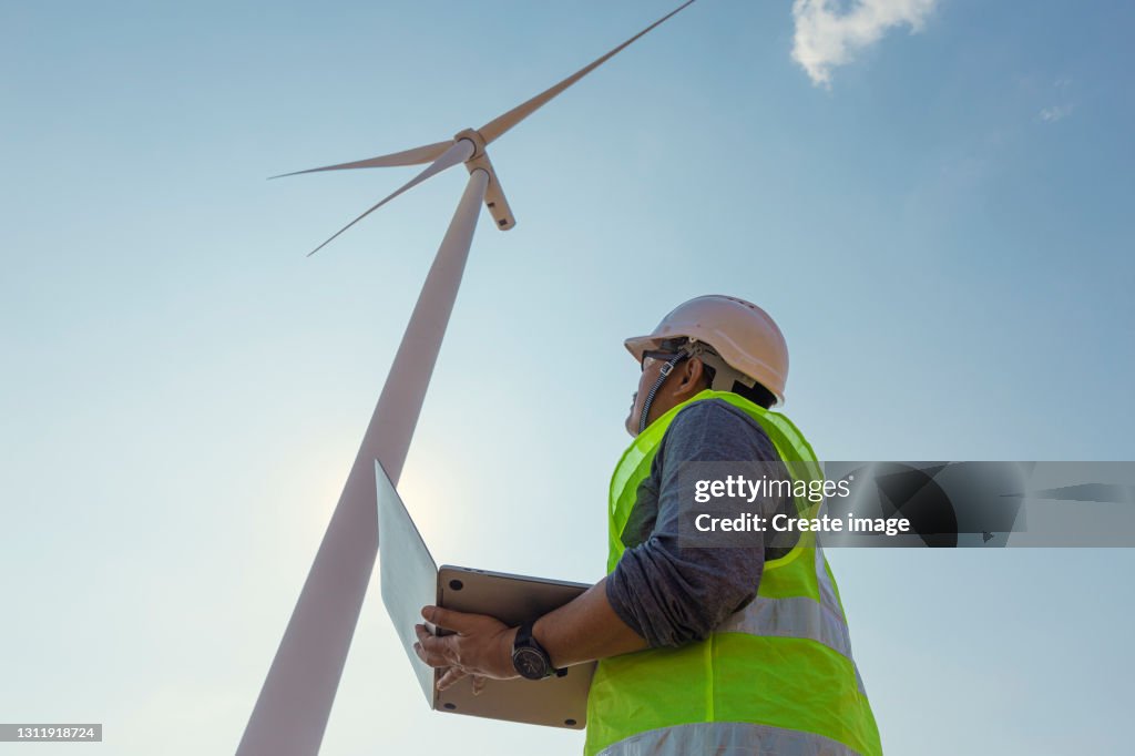 Middle aged Engineer using digital laptop for inspect quality control Efficiency Wind turbine for generating electric power, renewable energy, clean energy or environment conservation concept.