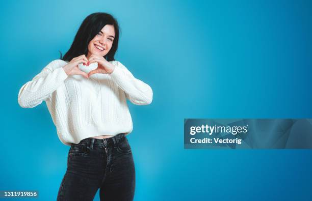 ritratto di bella giovane donna che mostra la forma del cuore con le mani. studio interno girato isolato. - amore a prima vista foto e immagini stock