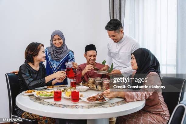 family and friends enjoying meal during hari raya celebration - eid family stock-fotos und bilder