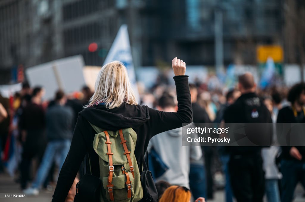 Vista trasera de una manifestante levantando el puño hacia arriba