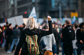 Rear view of a female protester raising her fist up