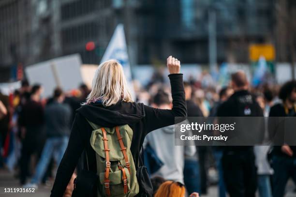 bakifrån av en kvinnlig demonstrant som höjer sin knytnäve upp - primärval bildbanksfoton och bilder