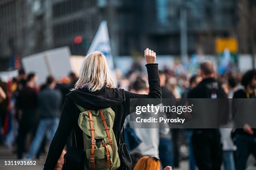 一名女抗議者舉起拳頭的后視圖 一名女抗議者舉起拳頭的后視圖