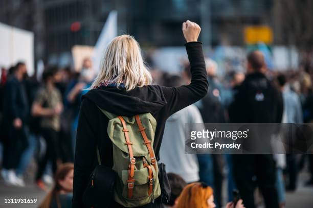 一名女抗議者舉起拳頭的后視圖 - 青少年組織 個照片及圖片檔