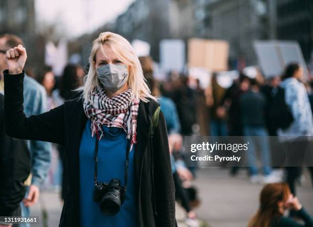 female protester raising her fist up a - mask confrontation stock pictures, royalty-free photos & images