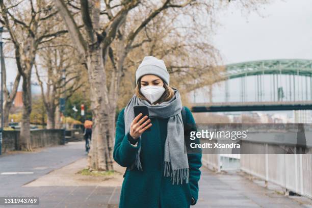 kvinna som bär en medicinsk mask och använder en telefon utomhus - kombinerad mobilitet bildbanksfoton och bilder