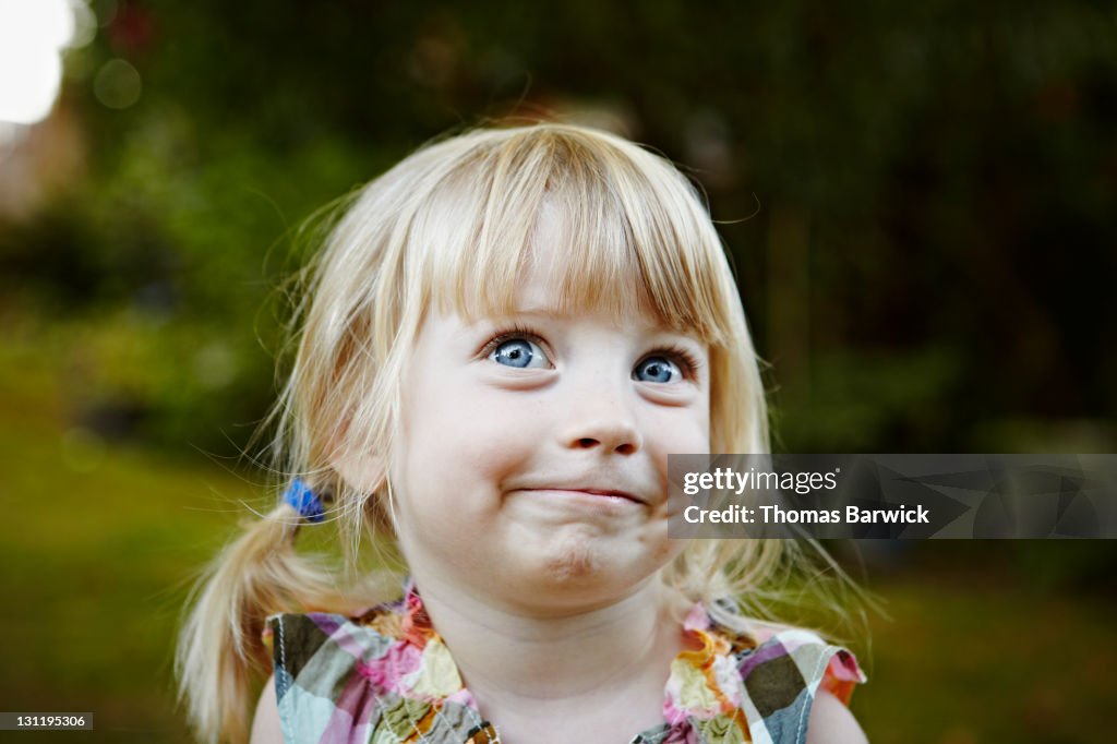 Young girl in backyard smiling looking up