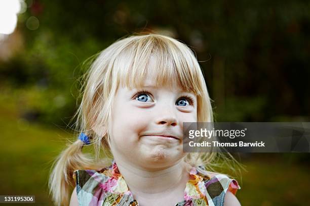 young girl in backyard smiling looking up - neugierde stock-fotos und bilder