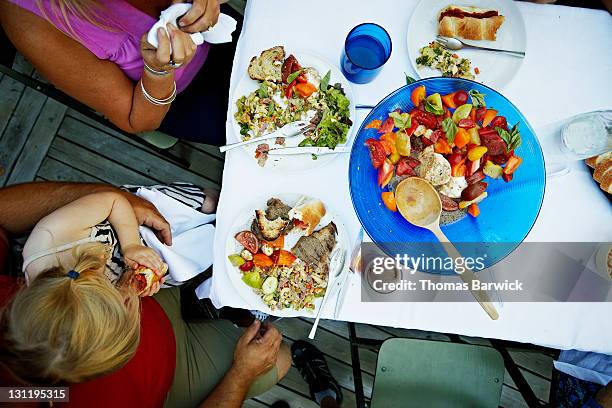 father holding daughter at outdoor dinner table - perfection salad stock pictures, royalty-free photos & images