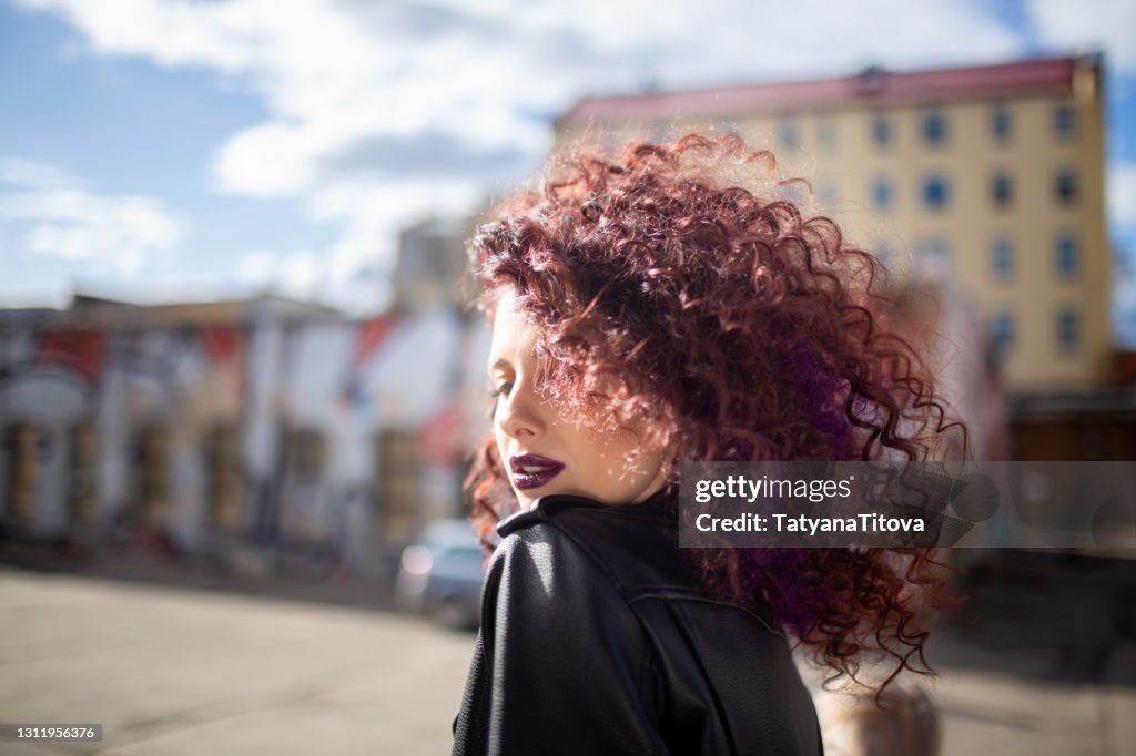 Fashion teenager girl with curly hair and purple lips posing