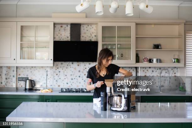 mujer desempacar en su nueva cocina - cafetera electrodoméstico fotografías e imágenes de stock