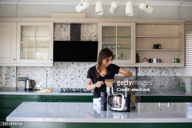 mulher desempacotando em sua nova cozinha - coffee maker - fotografias e filmes do acervo