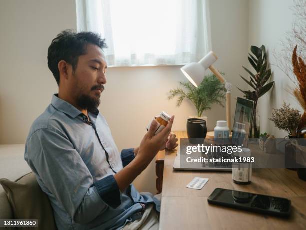 um homem asiático uma chamada de telemedicina de vídeo com um médico. - tomando remédio - fotografias e filmes do acervo
