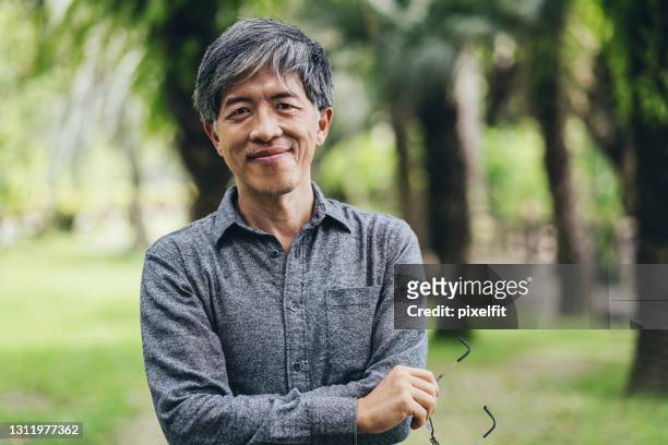de chinese etniciteitsmens van de medio leeftijd in het park - asian man stockfoto's en -beelden