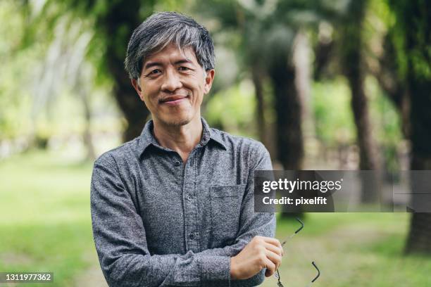 mid age chinese ethnicity man in the park - man asia stock pictures, royalty-free photos & images