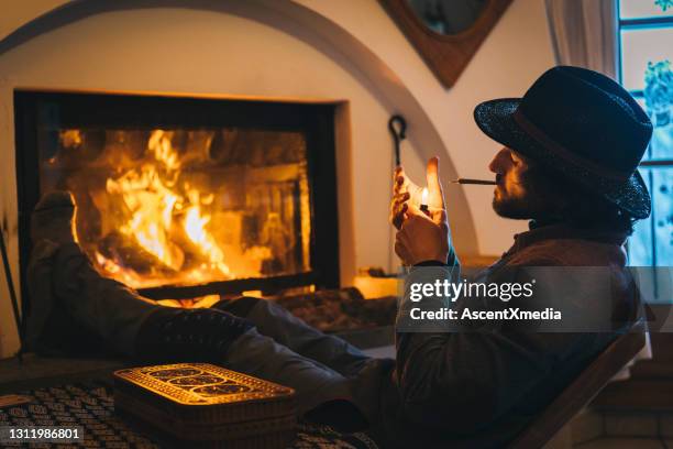 de jonge mens ontspant door brand en rookt cbdverbinding - haardvuur stockfoto's en -beelden