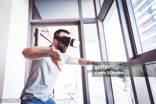 man wearing vr headset playing online gaming - emirati enjoy stock pictures, royalty-free photos & images