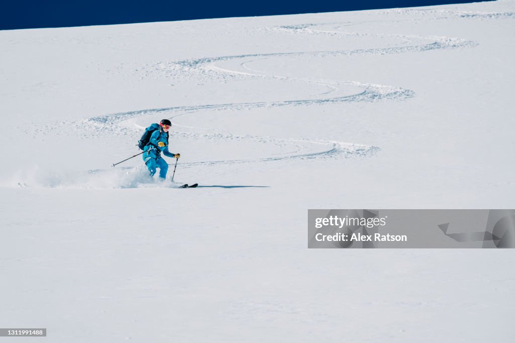 Female backcountry skier makes big turns on snow covered glacier