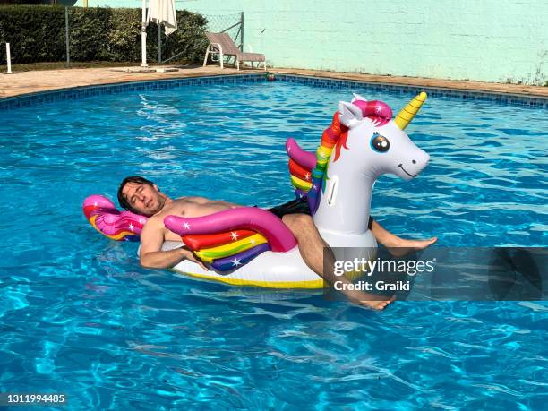 man lying and relaxed on top of the unicorn float. - schwimmring stock-fotos und bilder