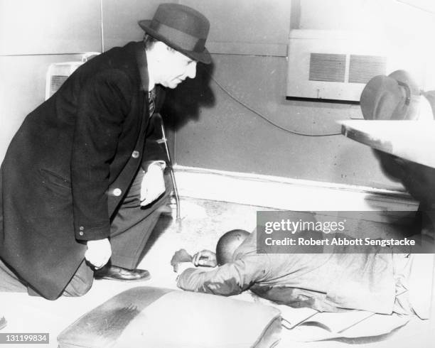 Unidentified police detectives examine the body of American politician 24th Ward Alderman Benjamin F. Lewis who had been assassinated in his office...
