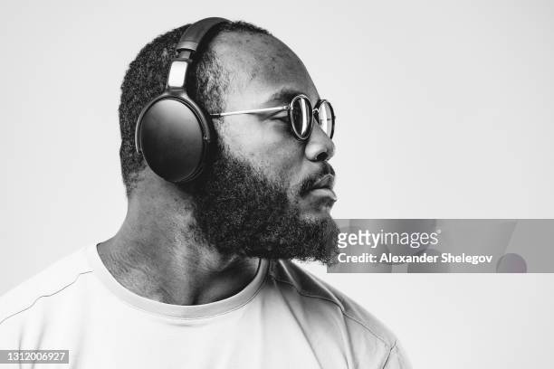 die afroamerikanische ethnizität im studio mit professionellen drahtlosen schwarzen kopfhörern hört musik. konzept für dj, pop, rap, r&b musikfotografie.  schwarzweißfoto mit kopierbereich - pop musician stock-fotos und bilder