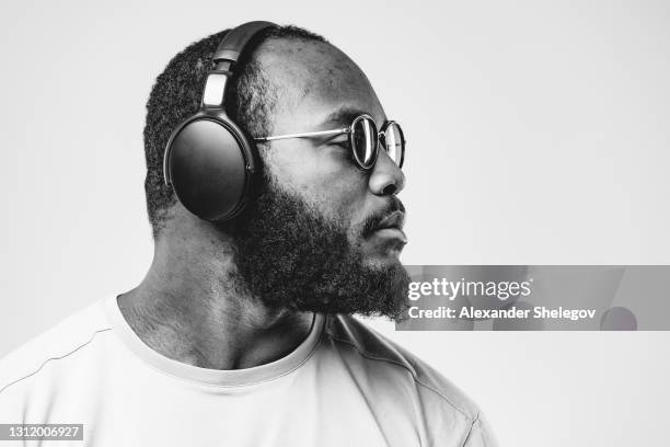 african-american ethnicity person at the studio with professional wireless black headphones is listening music. concept for dj, pop, rap, r&b music photography.  black and white photo with copy space - musician man stock pictures, royalty-free photos & images