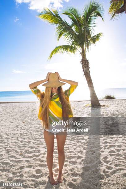 fun woman on tropical beach vacation, woman covering face with straw hat - strohoed stockfoto's en -beelden