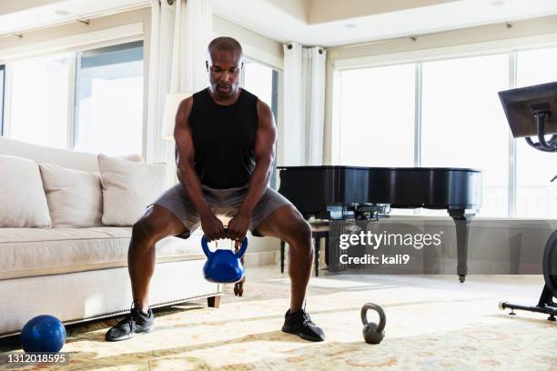 afrikaans-amerikaanse mens die thuis met kettlebells uitoefent - kettlebell stockfoto's en -beelden