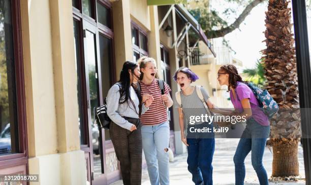 four tween girls walking on sidewalk outside building - group of teens arguing stock pictures, royalty-free photos & images