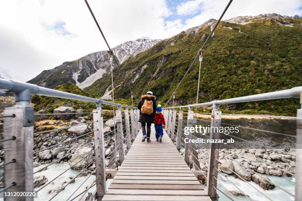 mother and son crossing a floating bridge. - new zealand holiday stock pictures, royalty-free photos & images