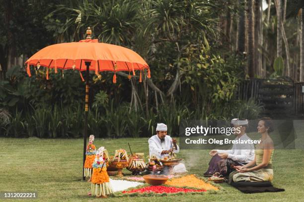 european couple on traditional bali wedding ritual blessing ceremony with balinese monk - hindu wedding ceremony stock pictures, royalty-free photos & images