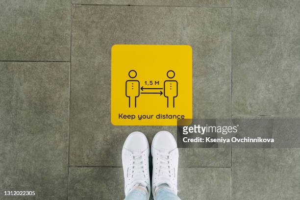 bilingual floor sticker with red and white thanking customers for practicing social distancing in both english and spanish. social distancing floor sign used during the coronavirus pandemic. - pavimenti foto e immagini stock