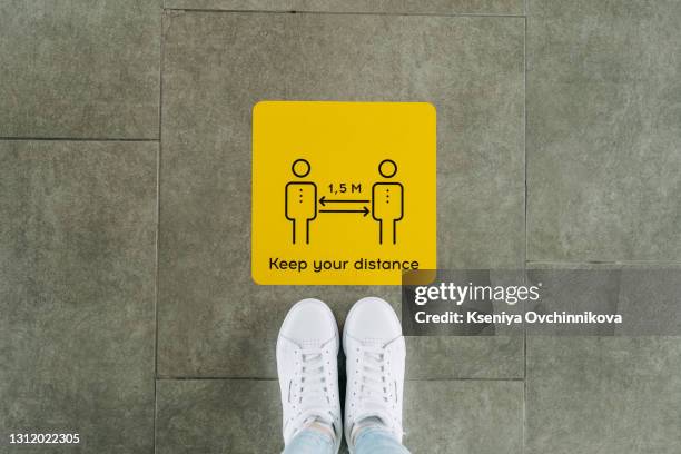 bilingual floor sticker with red and white thanking customers for practicing social distancing in both english and spanish. social distancing floor sign used during the coronavirus pandemic. - social distancing shopping stock pictures, royalty-free photos & images