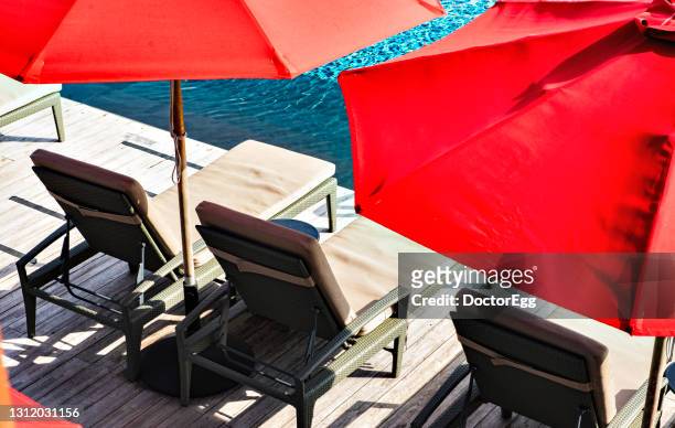 beach bed and red beach umbrella near swimming pool - multi coloured umbrella stock pictures, royalty-free photos & images