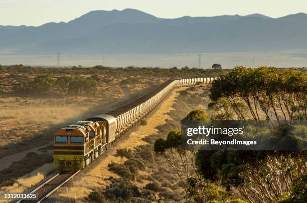morning sun glints off unit iron ore train with mountain range backdrop - tank car stock pictures, royalty-free photos & images