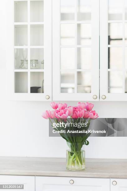pink tulips in vase stand on a wooden table near white wall. - flowers vase ストックフォトと画像