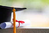Close-up of a mortarboard and degree certificate put on the table. Education stock photo