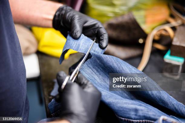 cutting a piece of denim with scissors from old jeans legs for patching - all denim stock pictures, royalty-free photos & images