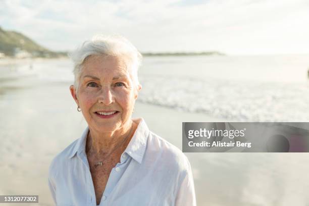 portrait of senior woman alone on beach - widow pension stock pictures, royalty-free photos & images