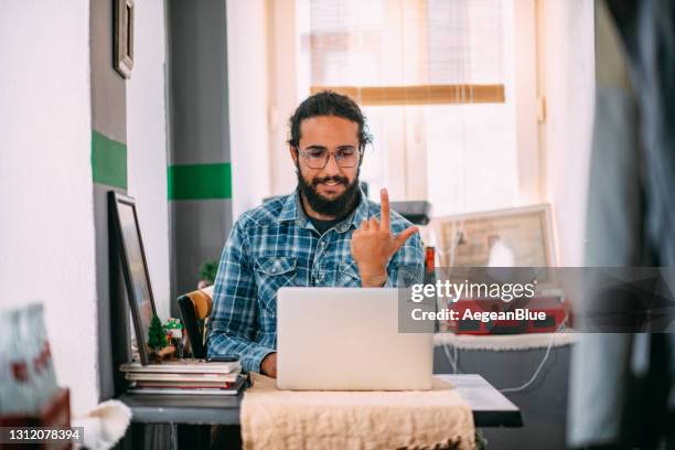 junger mann mit einem videoanruf mit gebärdensprache auf laptop - american sign language stock-fotos und bilder