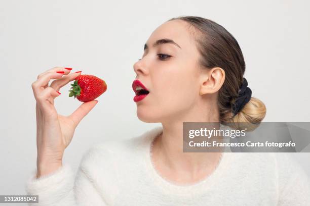 hispanic  young woman eats fresh strawberries - mouth open profile stock pictures, royalty-free photos & images