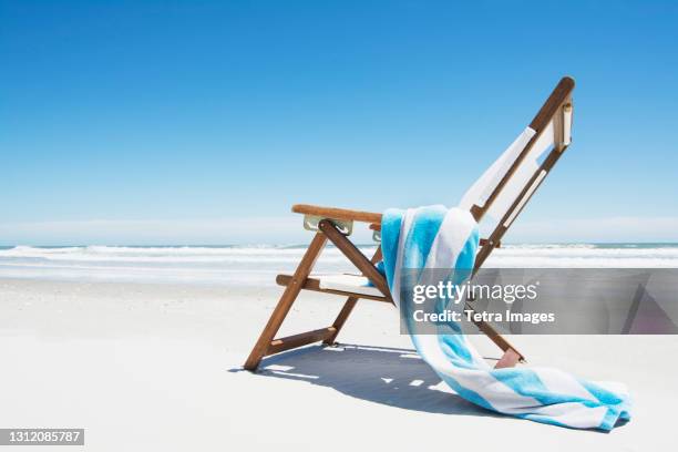 empty beach chair with striped towel on beach - telo da mare foto e immagini stock