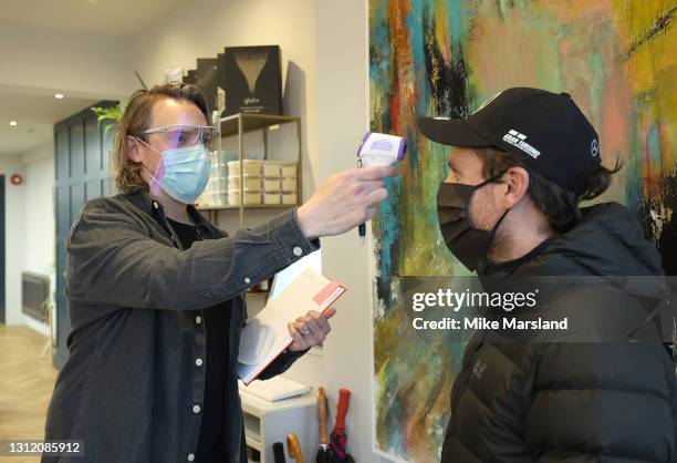 Owner of Trinder Hair Studios, Marc Trinder checks the temperature of his first customer Simon Amphlett after the easing of lockdown restrictions on...